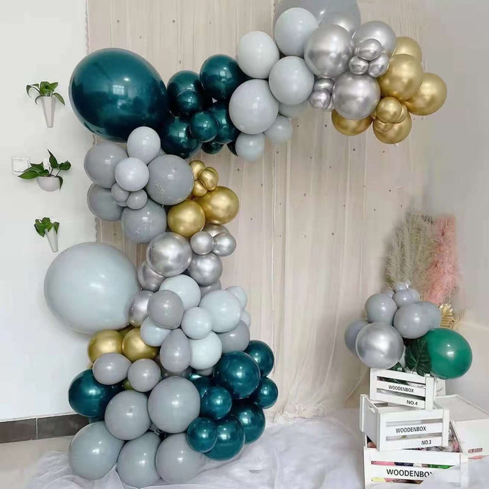 Balloon arch decoration in teal, gold, and silver tones.