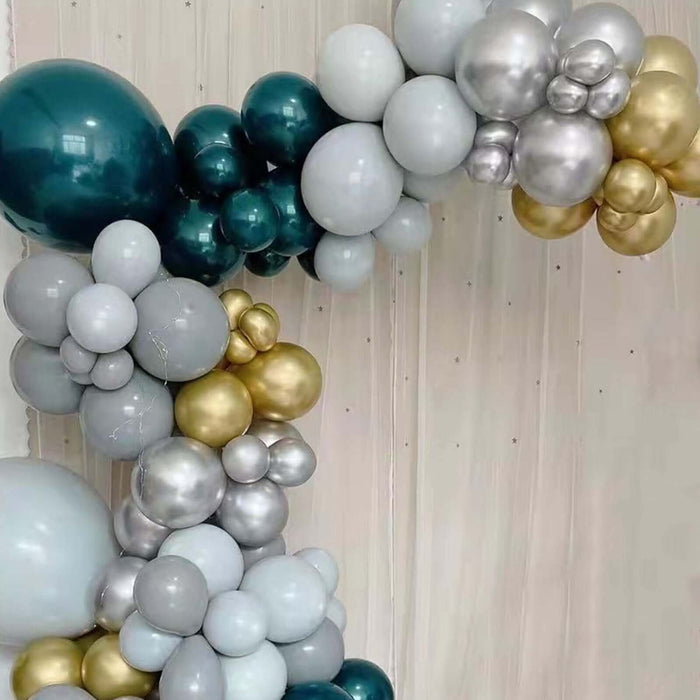 Balloon arch in teal, silver, and gold colors against a plain background. #whtbkgd