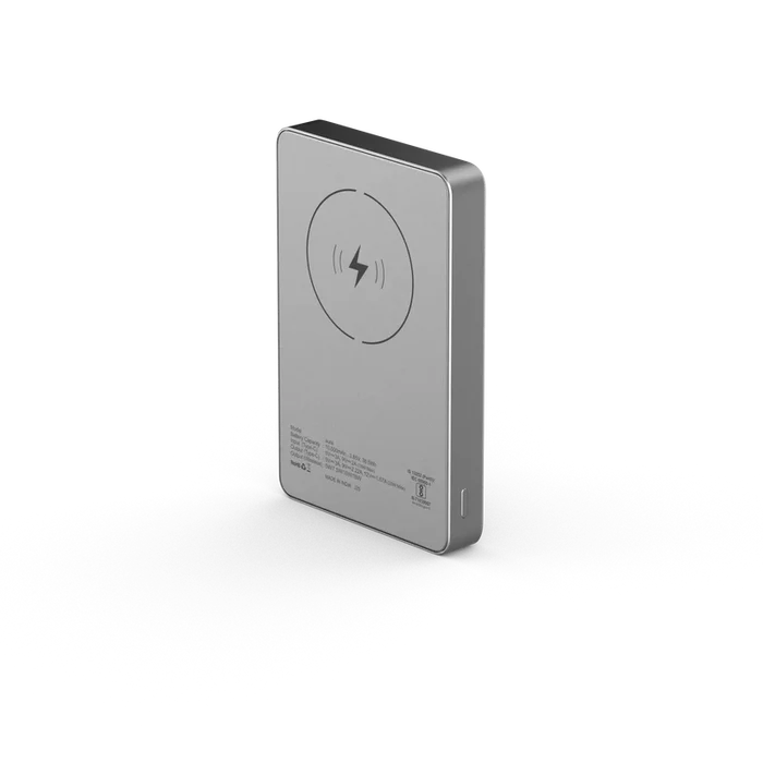 A slim rectangular portable power bank in brushed silver metal, shown at a three-quarter angle on a clean white background. The back features a circular wireless charging symbol and small printed specifications.