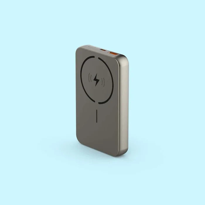 A slim, rectangular portable power bank in a metallic taupe-gray finish, featuring a black wireless charging symbol on its front face, set against a solid light blue background.