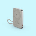 A silver portable power bank with a built-in wrist strap, featuring a Qi wireless charging pad on the back and a USB-C port on the side, set against a solid light blue background.