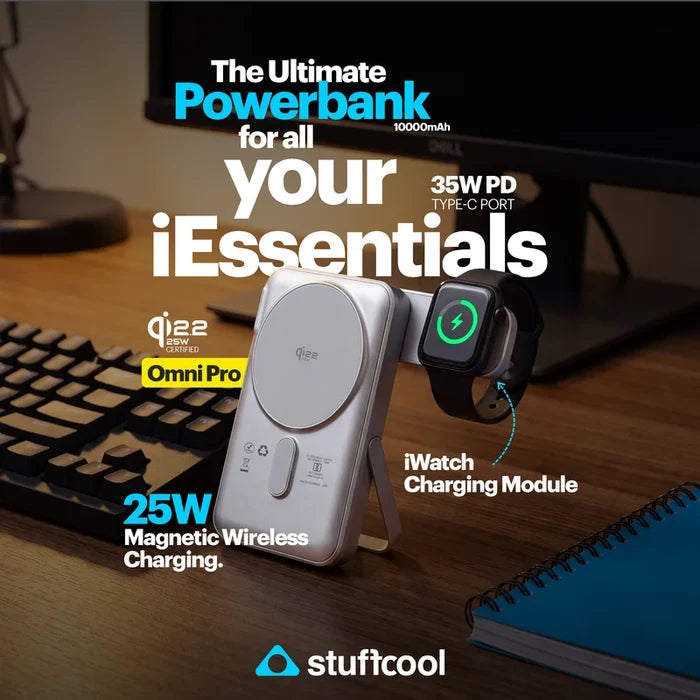 A silver Stuffcool Omni Pro power bank with built-in wireless charging pads, shown charging an Apple Watch on a wooden desk with a keyboard and monitor in the background. Text overlays highlight its 10000mAh capacity, 35W PD type-C port, 25W magnetic wireless charging, and Qi2.